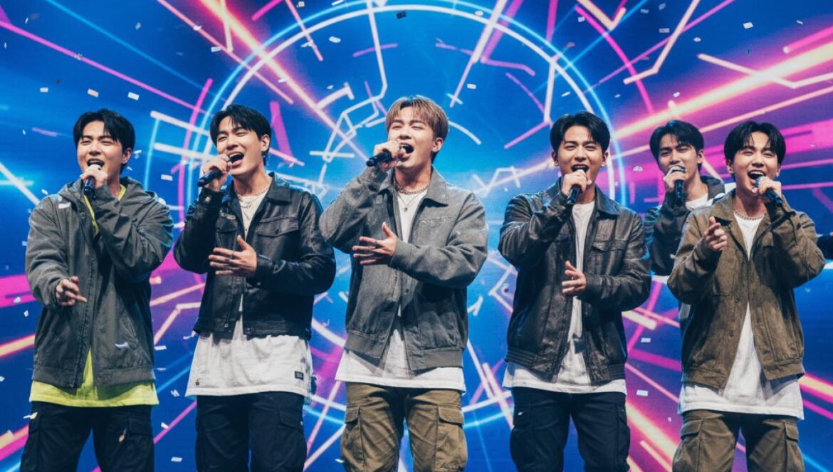 P1Harmony estrena “EX” en inglés y se atreve con español: lo que cambia para fans en Latinoamérica y España Seis idols en el escenario, cantando al micrófono con luces neón y pantallas LED detrás, energía de concierto y estética pop moderna.