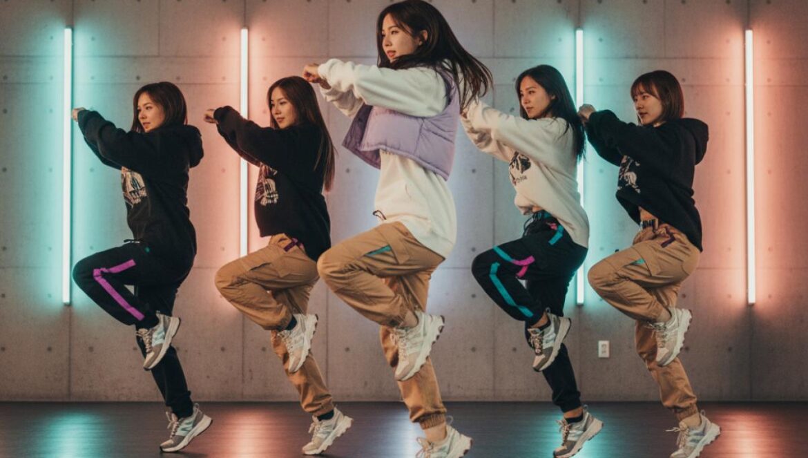 LE SSERAFIM y j-hope revientan iTunes con SPAGHETTI: 55 países al #1 y YouTube en llamas Grupo femenino de pop asiático ensayando una coreografía en estudio, vestuario urbano y luces LED.