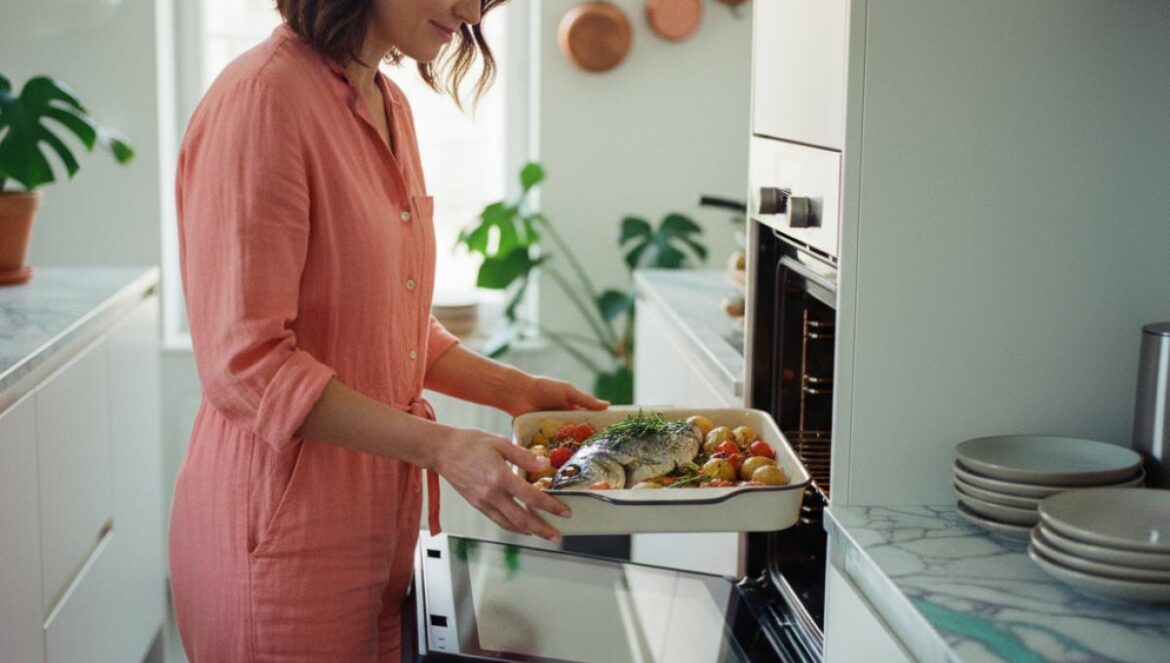 Pescado al horno crujiente sin freír: la técnica gaditana más ligera, barata y sin olores Bandeja de pescado al horno con patatas y tomates entrando en un horno doméstico.