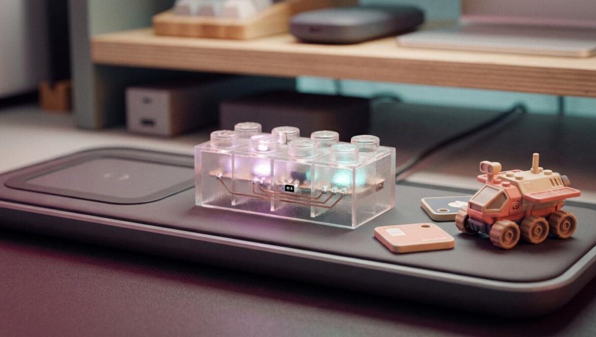 Lego Smart Brick: el ladrillo 2×4 con Bluetooth que cambia cómo se juega Un ladrillo plástico tipo bloque encajable sobre una base de carga inalámbrica, con luces suaves y pequeñas fichas con etiquetas cerca