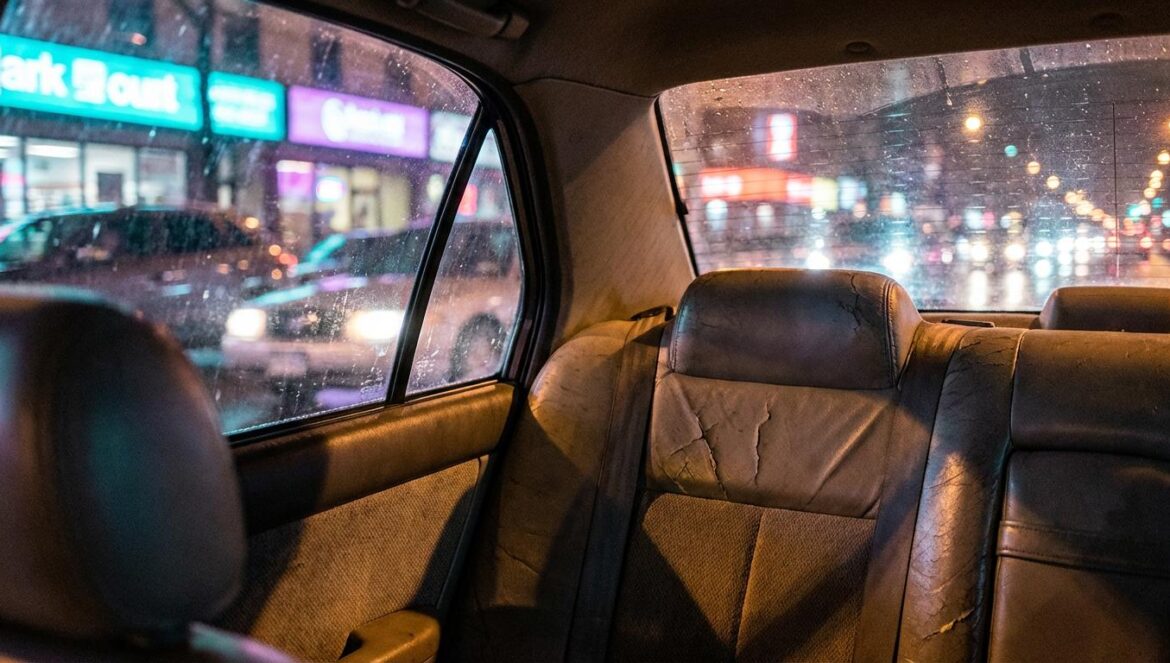 SATURN de zayALLCAPS: LA como rutina cinematográfica Asiento trasero de un coche de noche, con luces de ciudad reflejadas en la ventana y tráfico desenfocado al fondo.