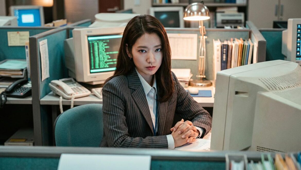 Undercover Miss Hong: Park Shin Hye explota en la oficina Park Shin Hye interpretando a Hong Geum Bo en una oficina de los años 90 con una expresión de enfado contenido y monitores antiguos al fondo.