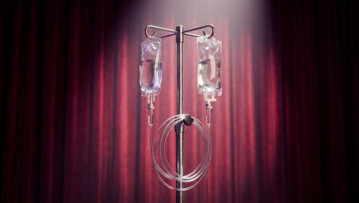 Megan Thee Stallion y su salud: el burnout en Broadway Un soporte de suero médico iluminado por un foco de teatro frente a cortinas de terciopelo rojo, simbolizando el agotamiento en Broadway.