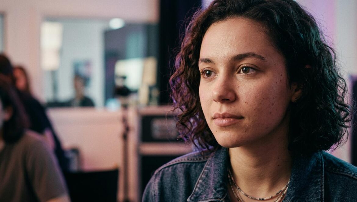 Ama regresa sin filtros: ¿Por qué su nueva era es vital? Primer plano de una mujer joven con expresión reflexiva bajo una iluminación ambiental tenue en tonos púrpuras y azules