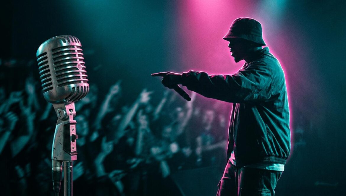 Silueta de un artista de hip-hop actuando en un escenario oscuro con luces de fondo magenta y turquesa, con un micrófono retro en primer plano.