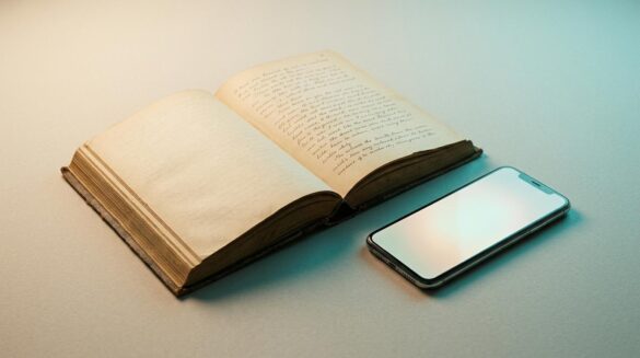 Margaret Atwood y la IA: por qué Claude no sabe de spoilers Un libro clásico abierto junto a un smartphone moderno sobre una mesa minimalista con iluminación de estudio cálida y fría.