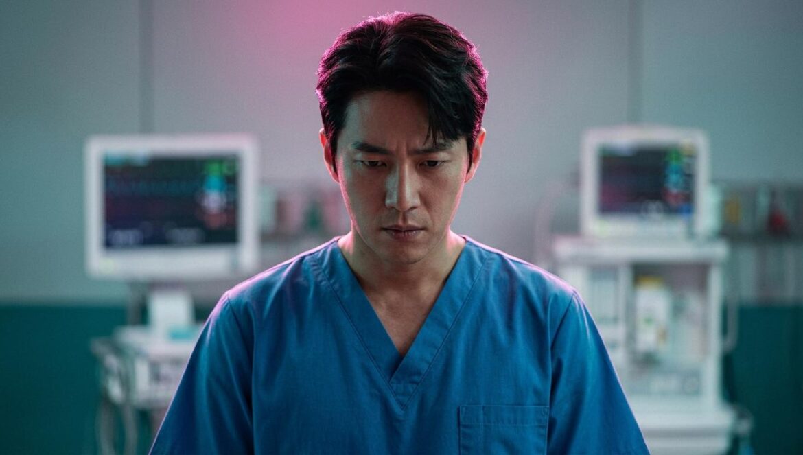 ¿Por qué The Husband redefine la moral del héroe? Primer plano de un actor coreano vestido de cirujano con expresión de tensión ética bajo luces de quirófano en tonos magenta y turquesa.
