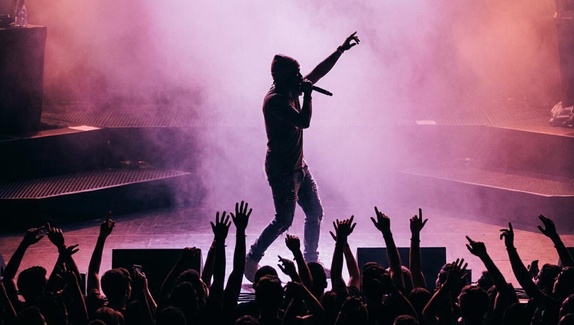Young Thug y ØWay: la apuesta que redefine el sonido de YSL Silueta de un artista de trap sobre el escenario iluminado con luces de color magenta y neblina lila durante un concierto en vivo.